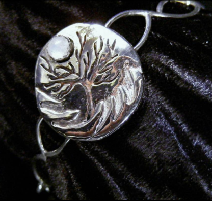 A sterling bracelet, fabricated overlay of silver on silver forming a tree with a moon of cabochon moonstone. c.2008